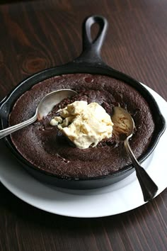 a chocolate cake with ice cream in a cast iron skillet on a wooden table