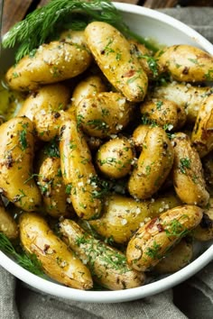 a white bowl filled with potatoes covered in herbs