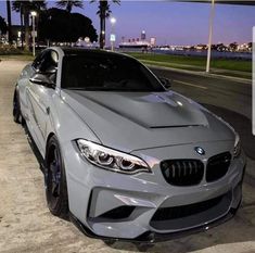 a silver car parked on the side of a road next to palm trees at night