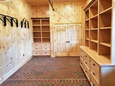 an empty walk in closet with brick flooring and wooden shelves on either side of the closet door