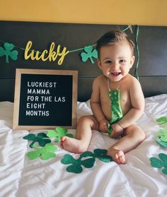 a baby sitting on a bed with shamrock decorations