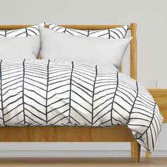 a bed with white and black pillows on top of it next to a wooden headboard