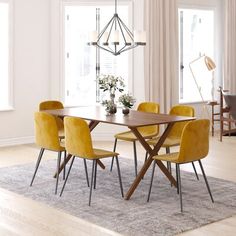 a dining room table with yellow chairs and a rug on the floor in front of it