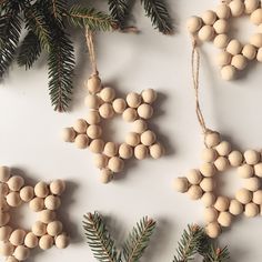 wooden ornaments are hanging from the branches of christmas trees on a white surface with pine cones and needles