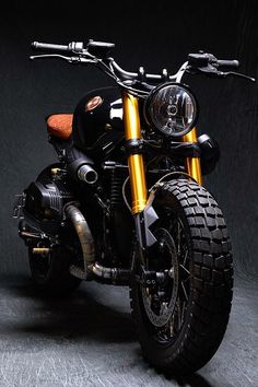 a black and gold motorcycle parked in a dark room with no one around the bike