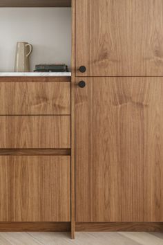 a wooden cabinet with two drawers and a coffee pot on the top shelf next to it