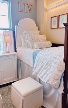 a white bed sitting next to a window in a room with blue walls and furniture