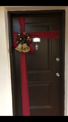 a black door with a red ribbon and bells on it