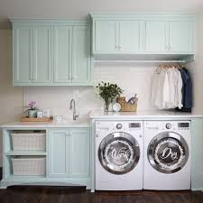 a washer and dryer in a laundry room with blue cabinets, white counter tops and wooden floors