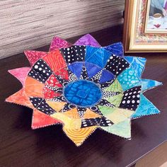 a multicolored flower sitting on top of a table next to a framed photo