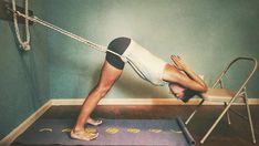 a woman is doing yoga on a hammock in a room with blue walls