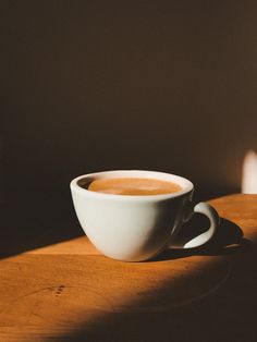 a cup of coffee sitting on top of a wooden table