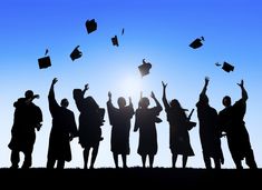 silhouettes of graduates throwing their caps in the air on graduation day, against a blue sky