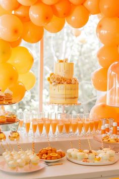 an assortment of desserts and drinks on a table with orange balloons in the background