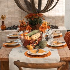 a table set for thanksgiving dinner with pumpkins, gourds and other decorations