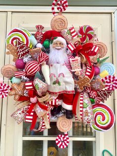 a christmas wreath with santa claus and candy canes hanging from the side of a building