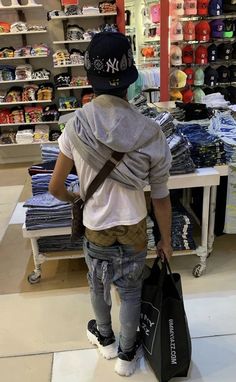 a young boy is looking at the shelves in a store with his back to the camera