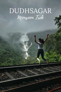 a woman jumping on train tracks in front of a waterfall with the words dudhsagar