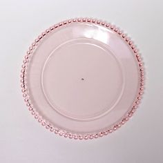 a pink plate with beaded edges on a white surface