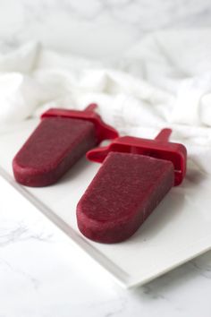 two pieces of red cake sitting on top of a white plate next to each other