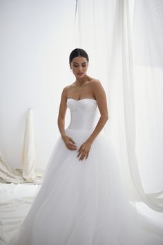 a woman in a white wedding dress posing for the camera with her hands on her hips