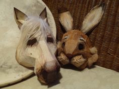 two wooden horse heads sitting next to each other on top of a wicker chair