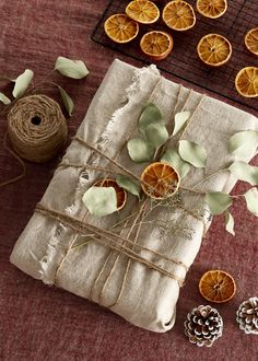 an orange slice tied to twine on top of a piece of cloth next to pine cones