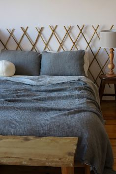 a bed with blue linens and pillows in a small room next to a wooden bench