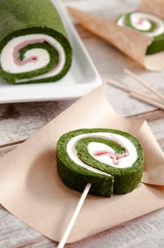 two plates with food on them and one has a green spiral shaped lollipop