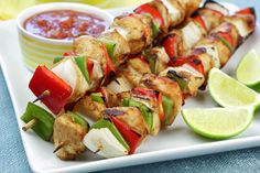 chicken and vegetable kabobs on skewers with salsa, lime wedges and ketchup