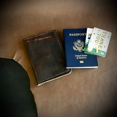 two passport cases sitting on top of a couch next to an american passport and money