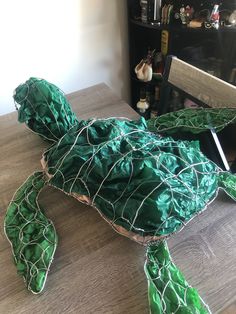 a paper mache turtle sitting on top of a wooden table next to a chair