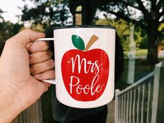 a person holding a coffee mug with the words mrs poole on it and an apple