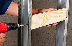 a man is using a drill to attach a piece of wood in a metal frame