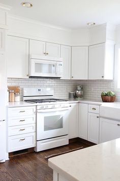 a kitchen with white cabinets and an oven in the center, along with wooden flooring