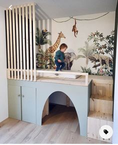 a young boy is playing in his playroom with giraffes on the wall