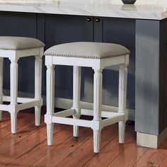 two white stools sitting next to each other on top of a hard wood floor