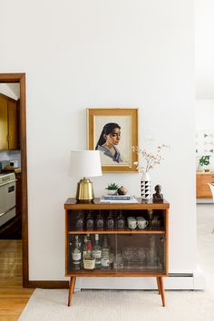 a table with bottles on it in front of a painting and a framed portrait above it