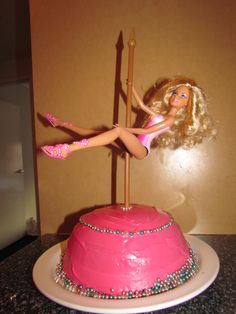 a barbie doll sitting on top of a pink cake with a spear sticking out of it