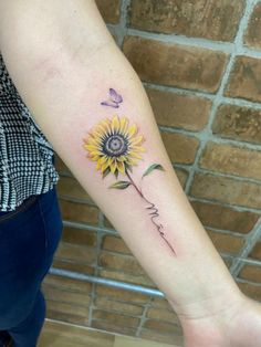 a woman's arm with a sunflower and butterfly tattoo on the left forearm