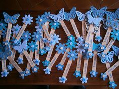 blue paper flowers and butterflies are arranged in rows on a wooden table with name tags attached to them