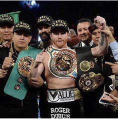 a group of men standing next to each other holding up their boxing belts in front of them