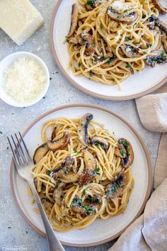 two plates of pasta with mushrooms and parmesan cheese