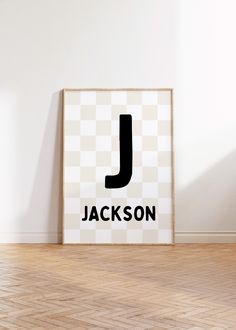 a poster with the letter j on it in front of a white wall and wooden floor