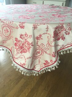 a red and white table cloth with tassels on it sitting on top of a wooden floor