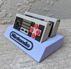 an old nintendo game console sitting on top of a blue stand next to a wall