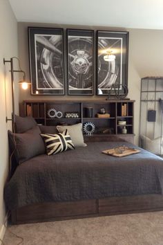 a bed with two framed pictures above it and pillows on the bottom, in front of a bookcase