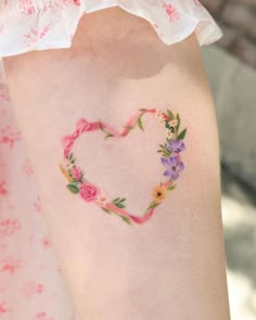 a heart shaped tattoo with flowers painted on the back of it's arm,