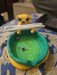 a yellow and green bowl sitting on top of a table with a stick sticking out of it