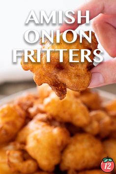 a hand holding up a fried onion fritter over a bowl of fried food